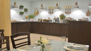 Un coin repas avec une table dressée pour quatre personnes, agrémenté d’un vase de fleurs, d’assiettes et de couverts.