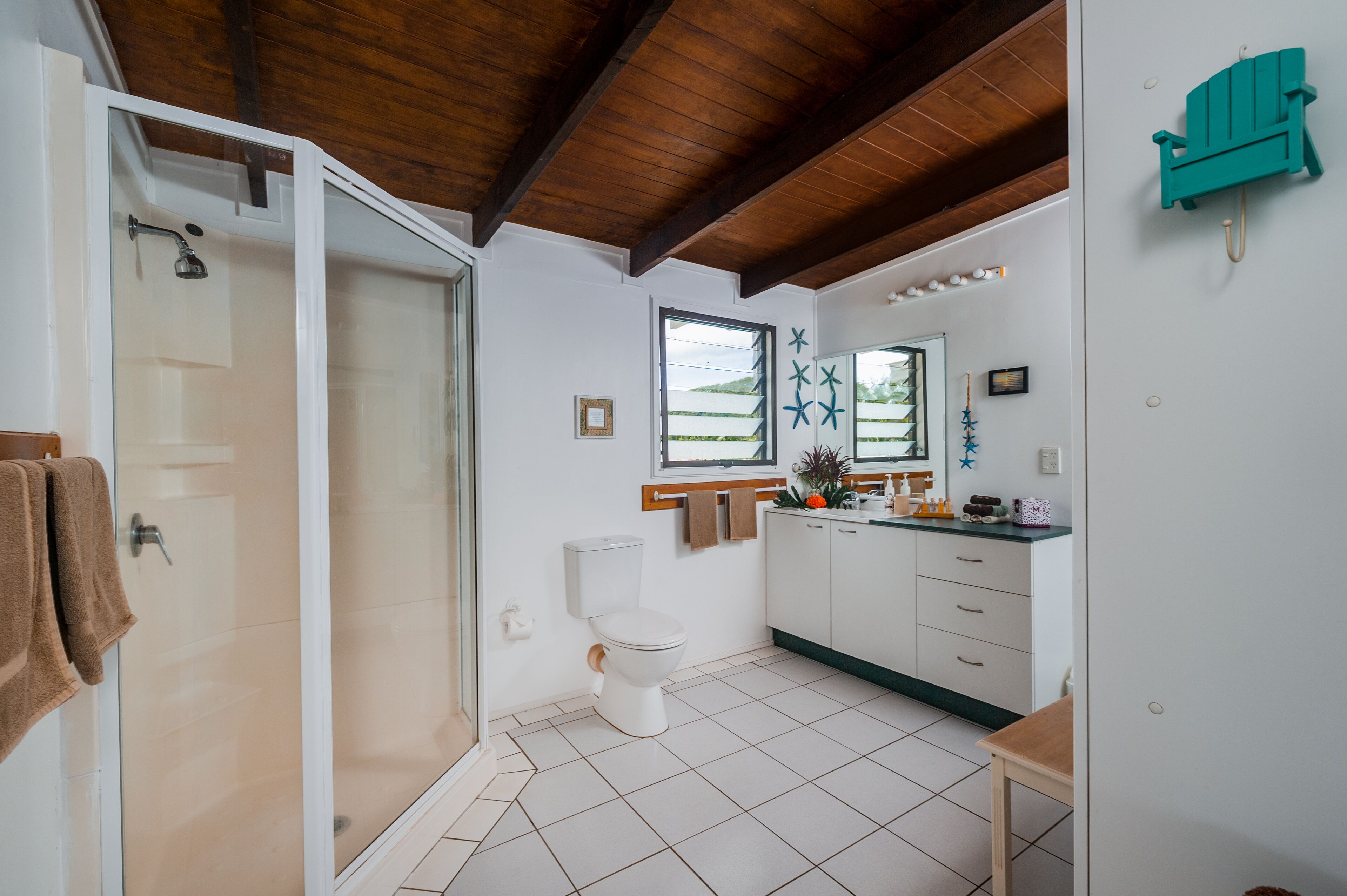 Ein Badezimmer mit Duschkabine, Toilette und Waschbecken mit Spiegel.