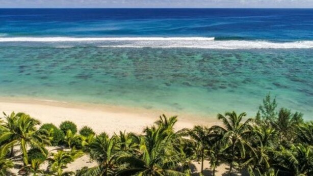 A beach with clear turquoise water, white sand, and palm trees. - The Cooks Oasis (Rarotonga)
