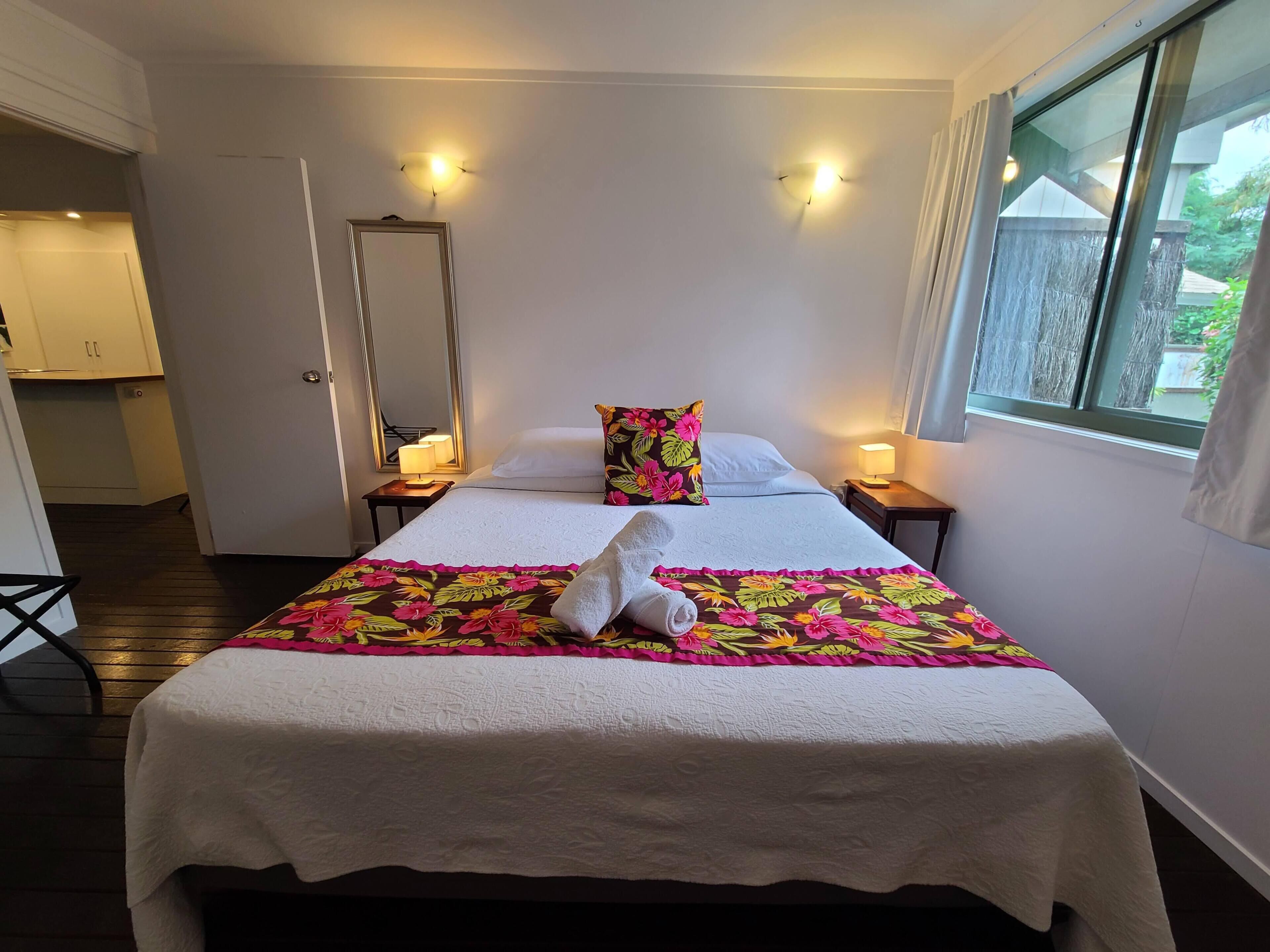 A hotel room with a bed, two bedside tables, a mirror, and a window.