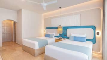 A hotel room with two beds, a ceiling fan, a nightstand with a phone, and a wall-mounted light fixture.