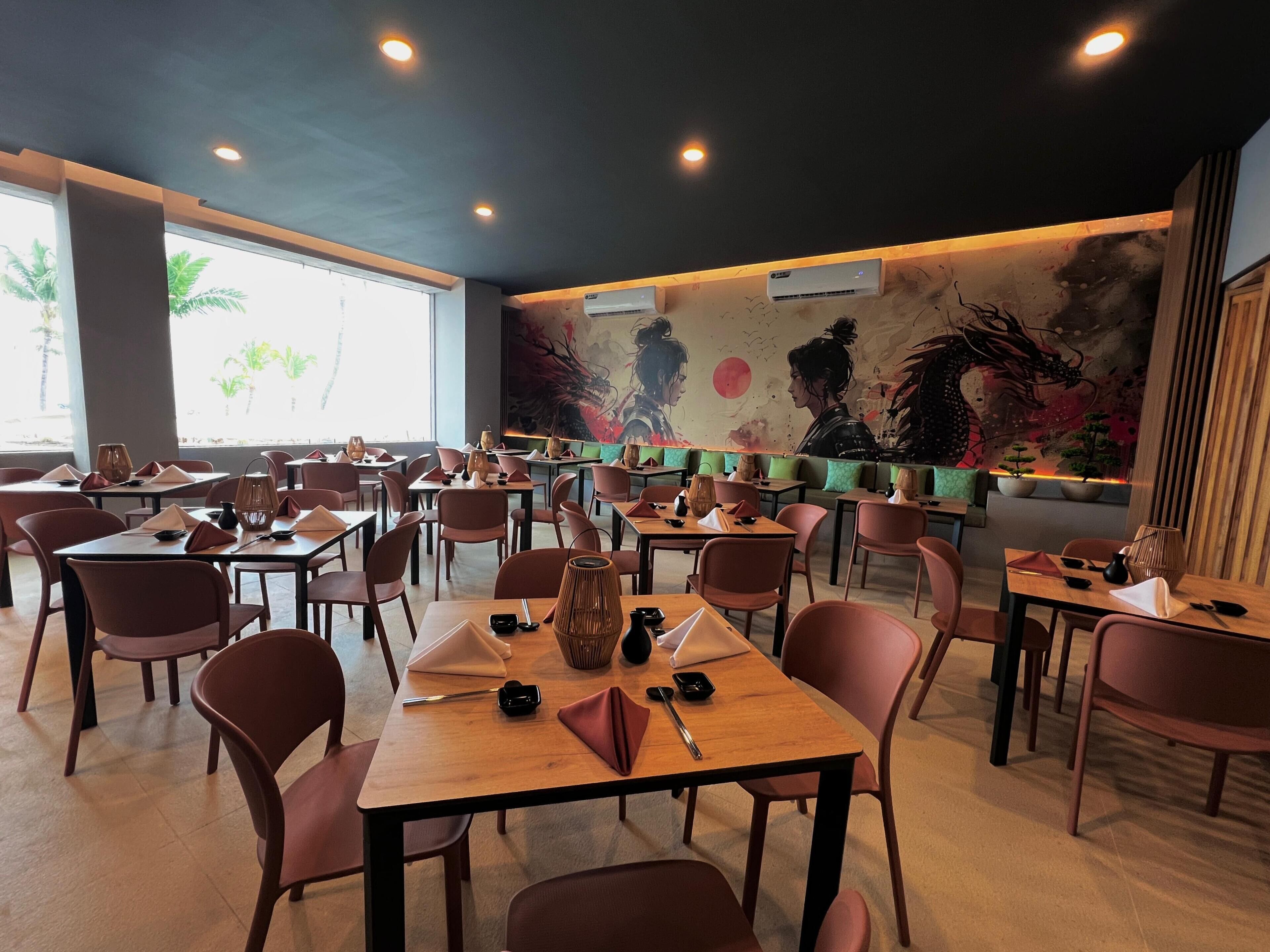 A restaurant with multiple tables and chairs, large windows, and a mural on the wall.
