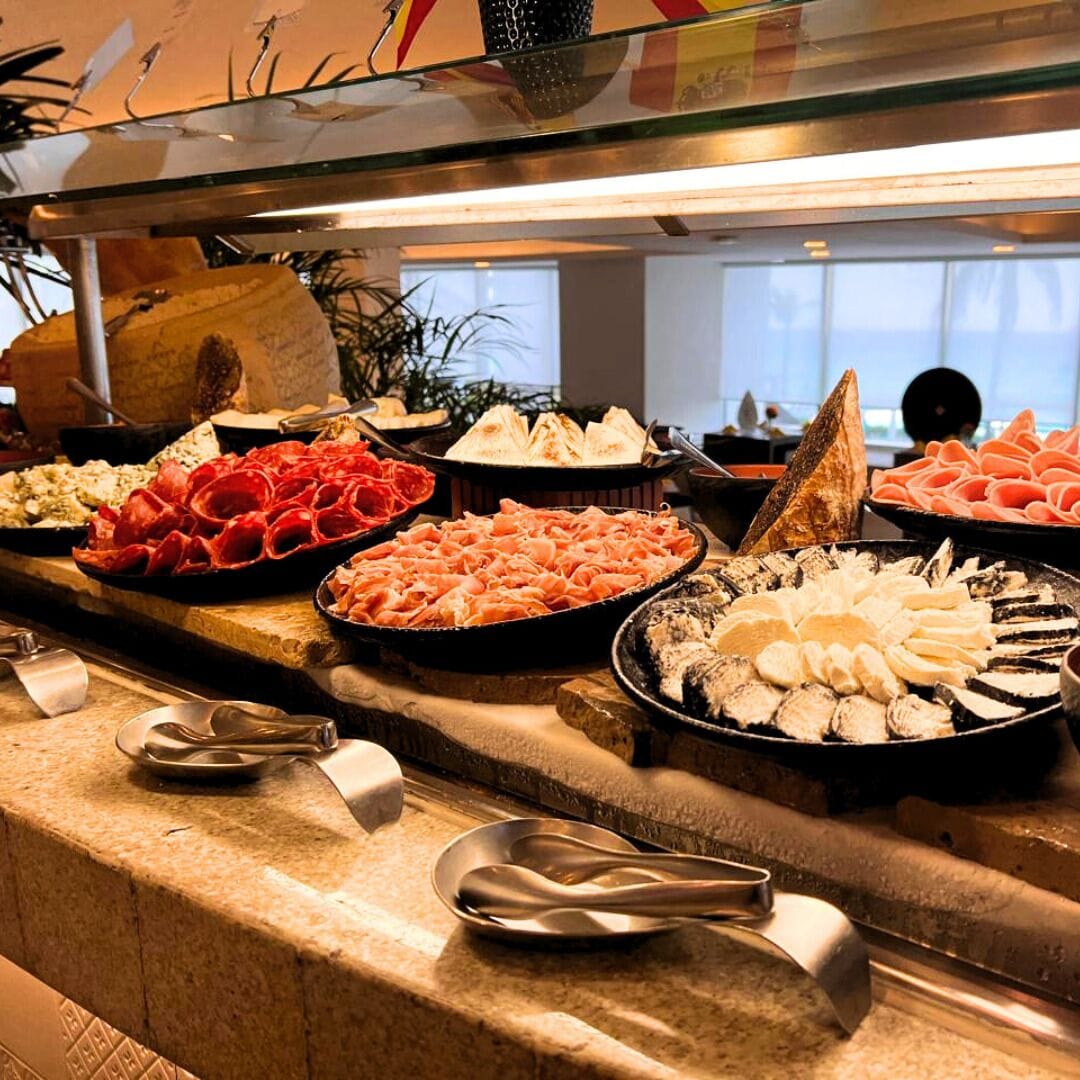 A buffet with various meats and cheeses.
