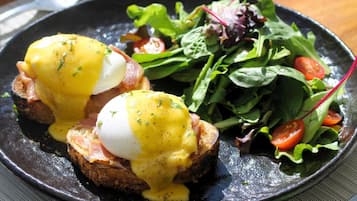 A plate with eggs benedict and a side salad.