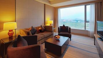 Una habitación de hotel con sofá, sillones, una mesita de centro y televisión.