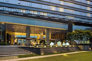 Un edificio moderno con fachada de vidrio, zona de estar al aire libre y entrada bien iluminada.