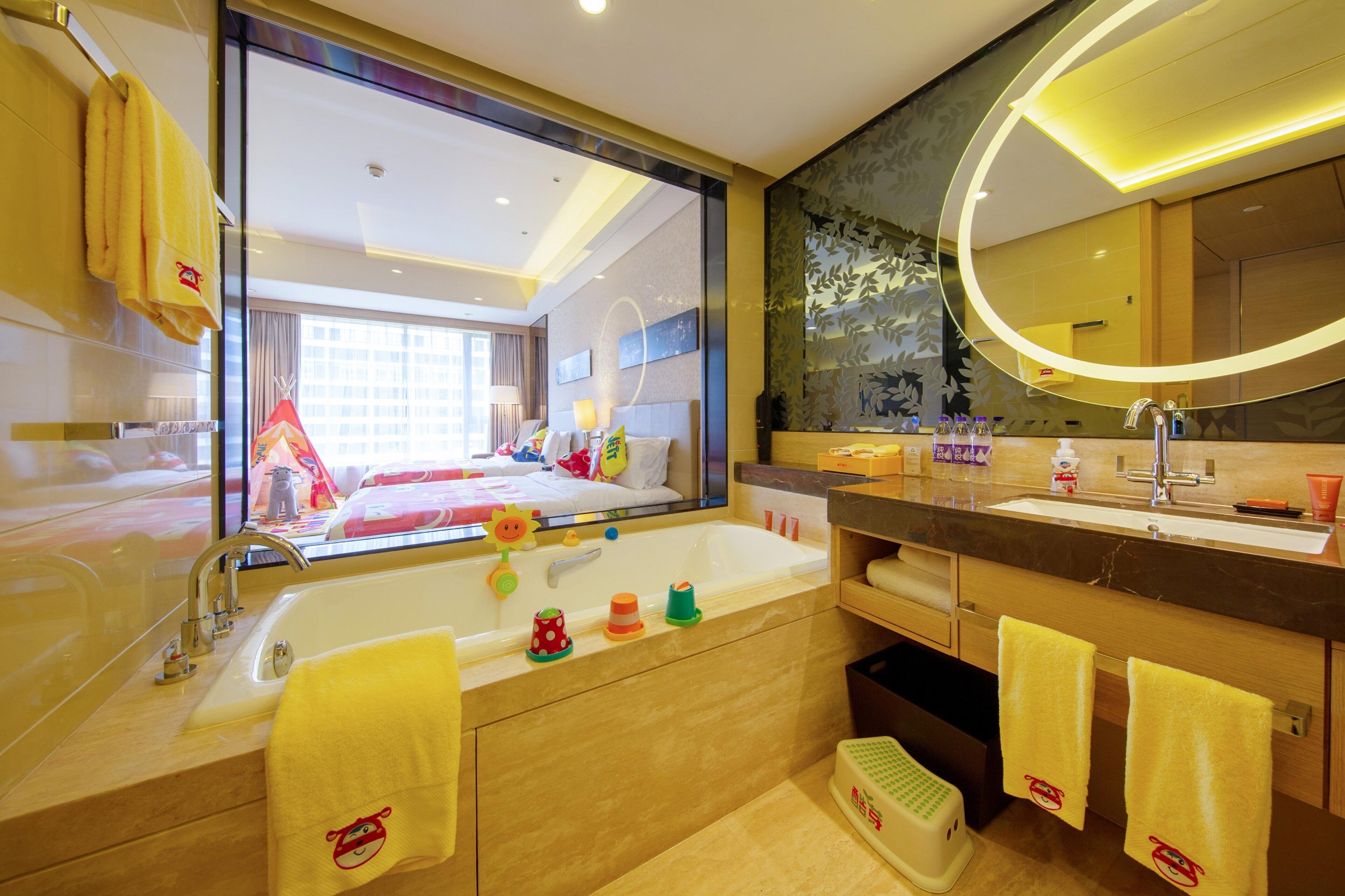 Une salle de bain d’hôtel avec une grande baignoire, un miroir et une vue sur la chambre adjacente.