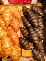 Un tagliere di legno con diversi croissant disposti sopra.
