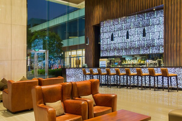 A modern lobby with leather sofas, a bar area, and a large illuminated wall. - Crowne Plaza Guangzhou Huadu by IHG (Guangzhou)