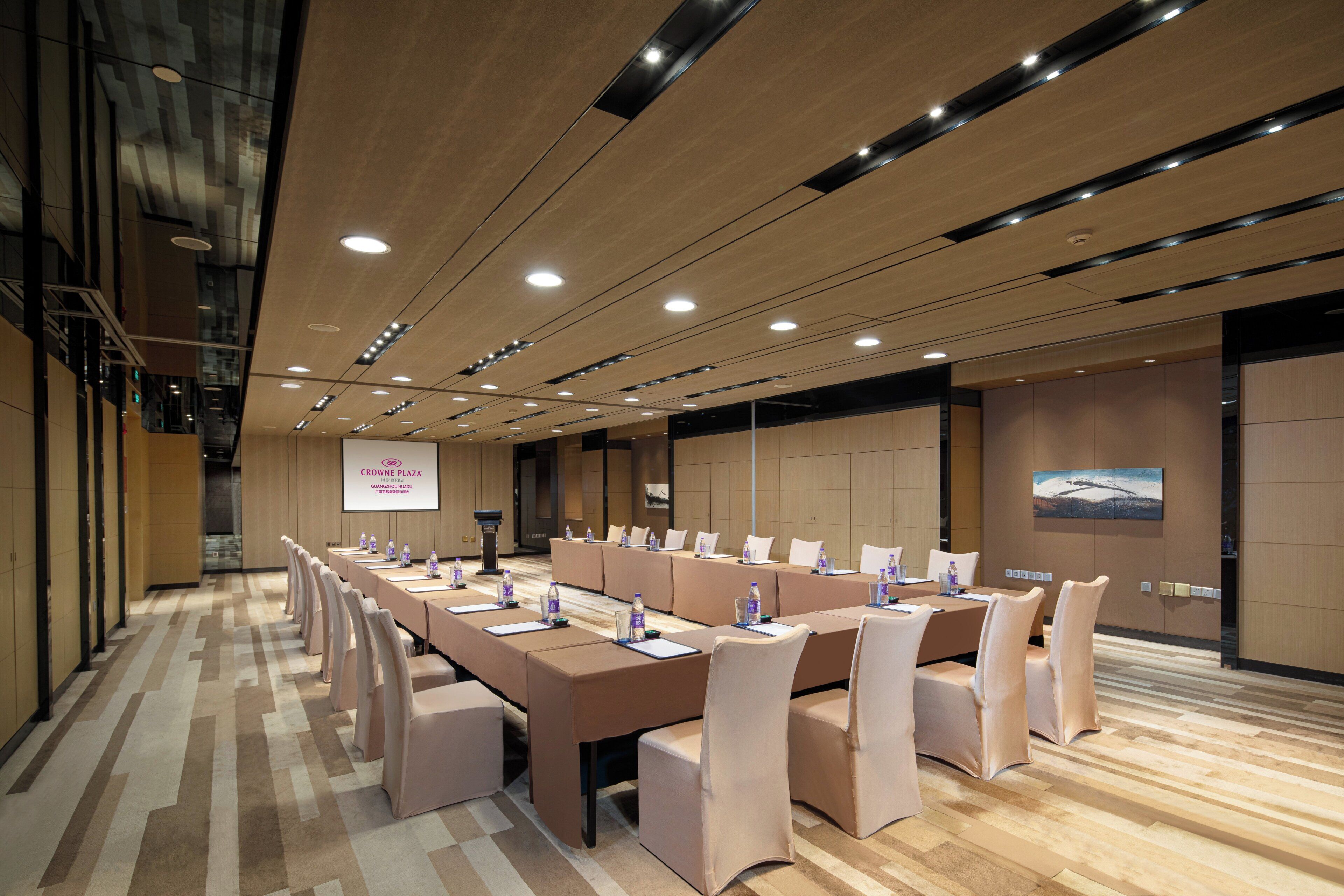 A conference room with a long table, chairs, and a presentation screen.