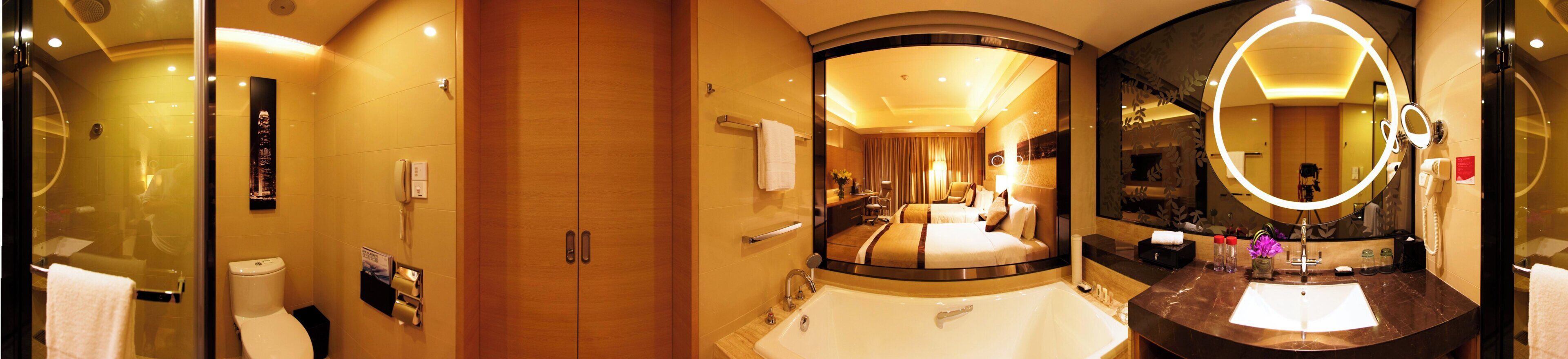 Un baño de hotel con un espejo grande, un inodoro y una zona de ducha.