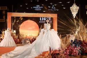 Hochzeitliche Dekoration mit einer Braut im weißen Kleid, einer großen Mondkulisse und Blumenarrangements.