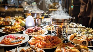 Una mesa con diversos platos, incluyendo mariscos y sushi, además de una olla hirviendo.