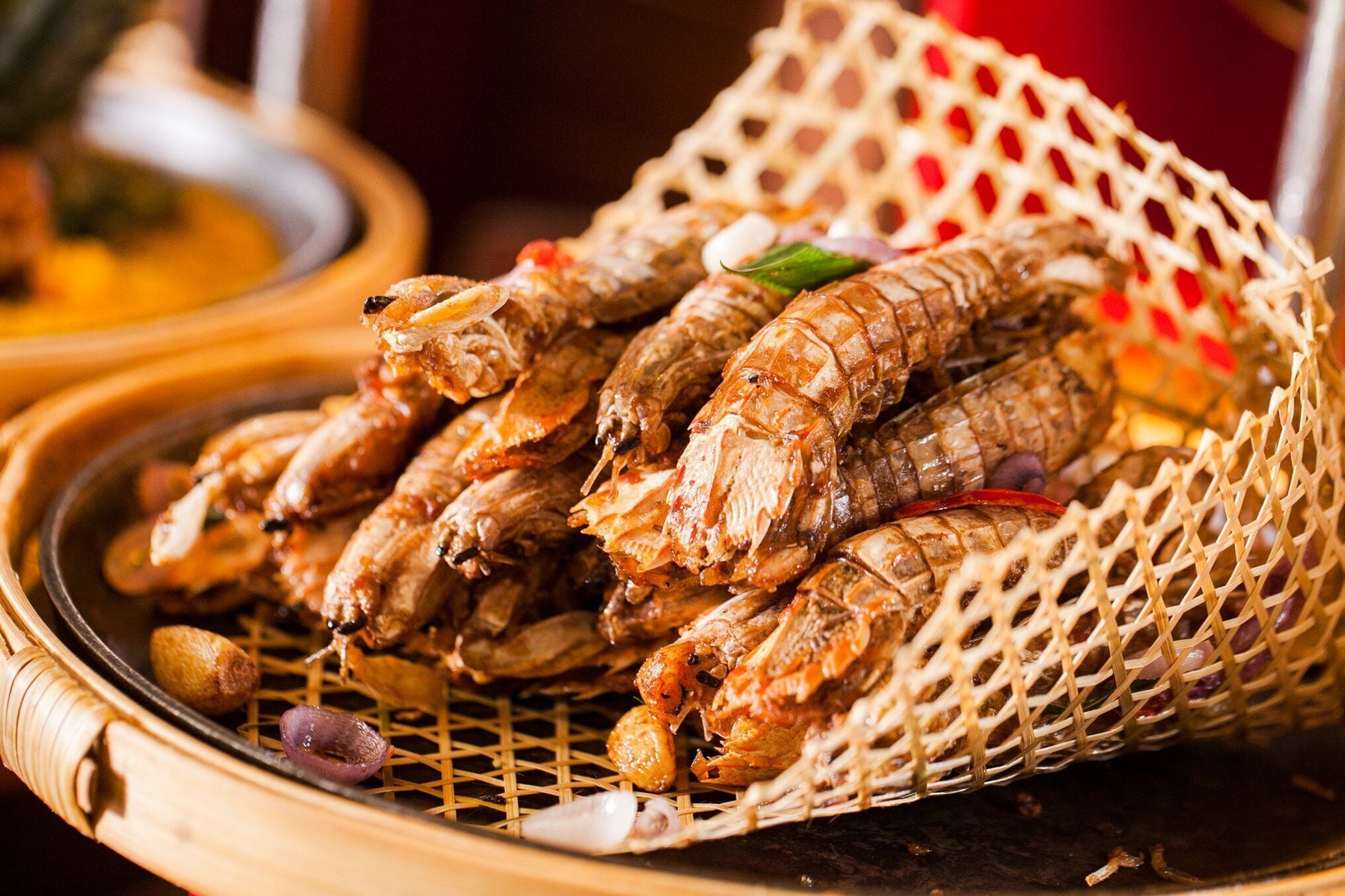 Een mand met gekookte zeevruchten, mogelijk garnalen, met een gevlochten mand en een grill.