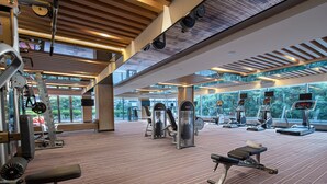 A spacious gym with various exercise equipment, large windows, and a modern ceiling design. - Crowne Plaza Guangzhou Huadu by IHG (Guangzhou)