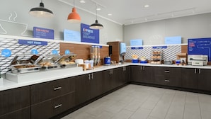A modern breakfast area with a counter displaying hot food, a bakery section, and a fruit station. - Holiday Inn Express Hotel & Suites Tullahoma by IHG (Tullahoma)