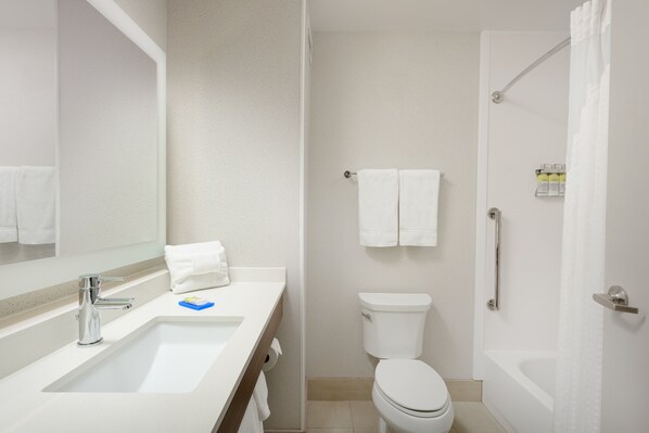 Un baño moderno con lavabo, espejo, inodoro y bañera.
