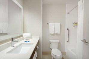 A modern bathroom with a sink, mirror, toilet, and bathtub.