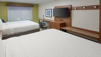 A hotel room with two beds, a desk, a chair, a television, and a window with blinds.