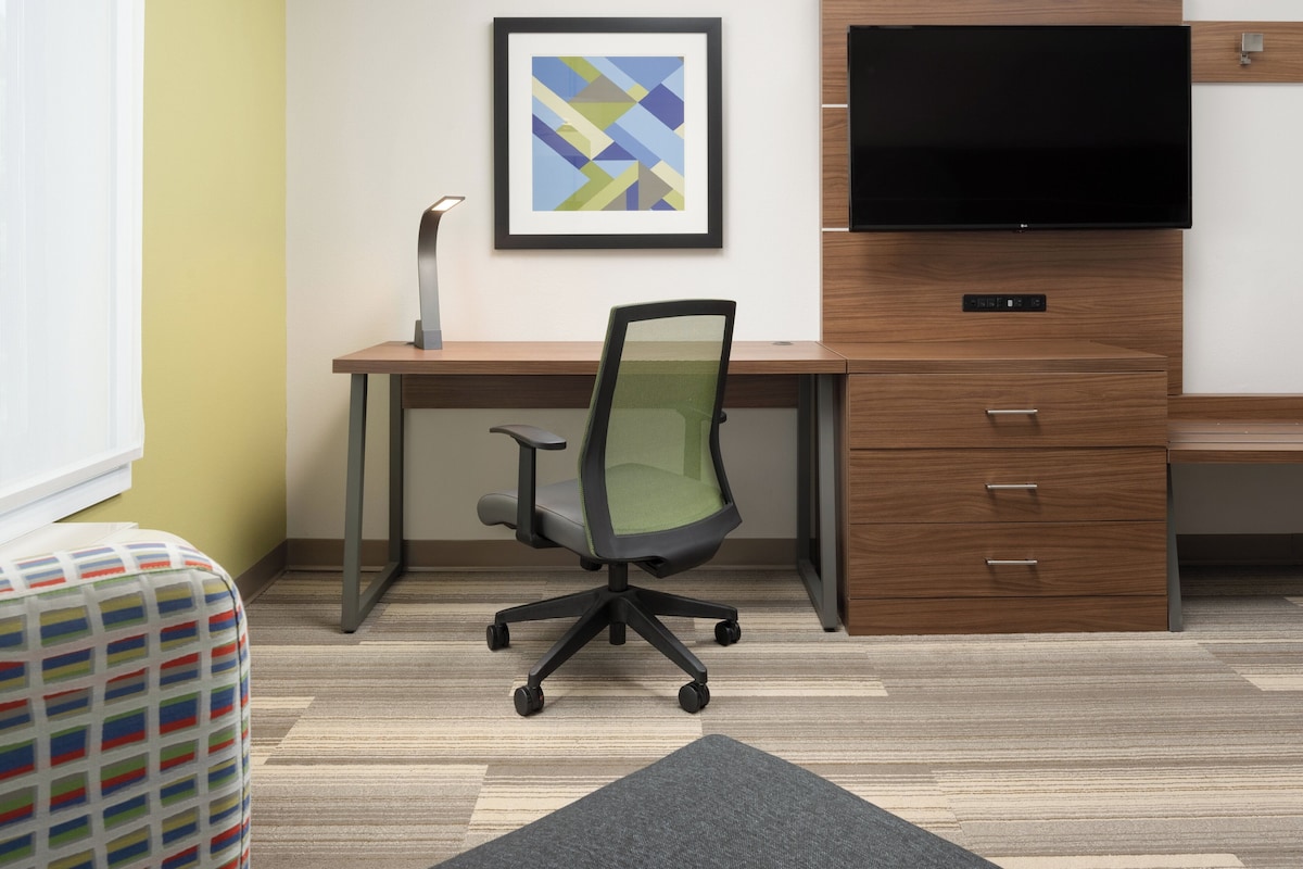 A modern office space with a desk, chair, and a TV mounted on the wall.