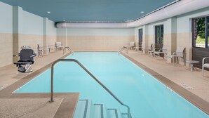 A swimming pool with a clear blue water, surrounded by chairs and a wheelchair. - Holiday Inn Express Hotel & Suites Tullahoma by IHG (Tullahoma)