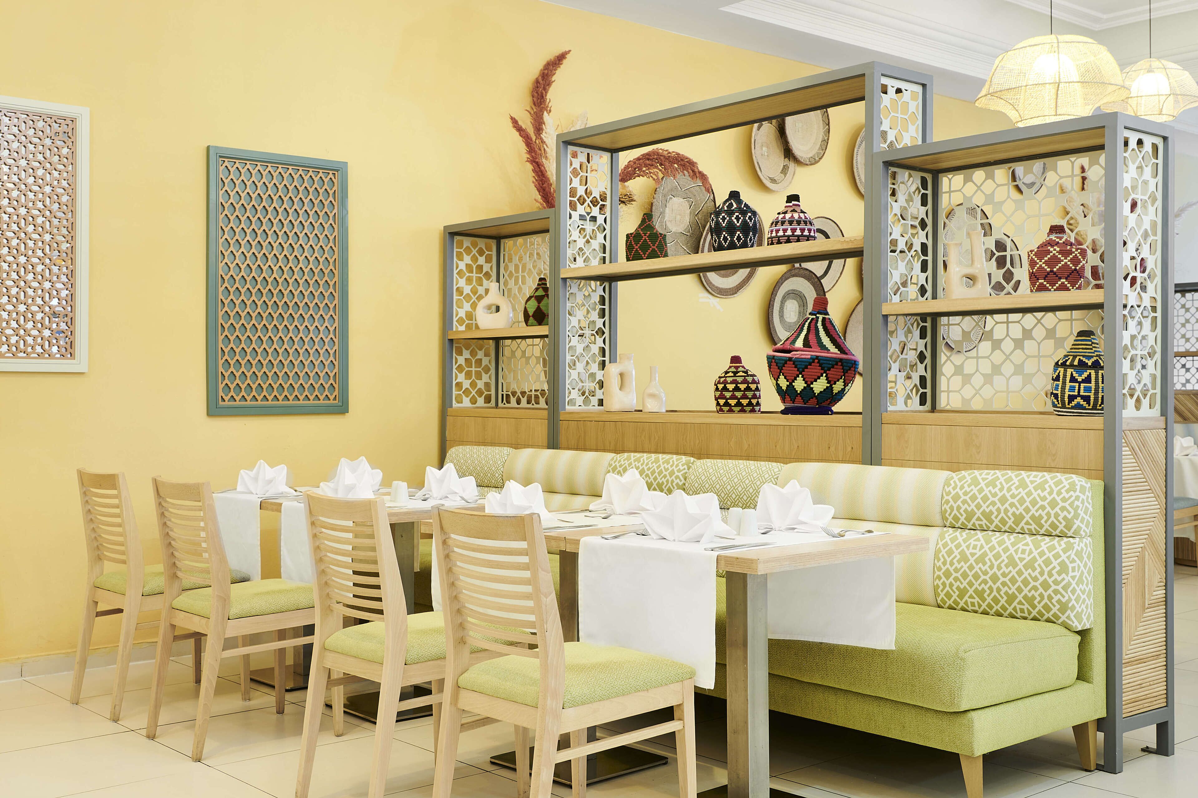 A dining area with a green sofa, wooden chairs, and a table set for four.