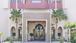 Un edificio con fachada rosa, ventanas de arco y entrada con azulejos.