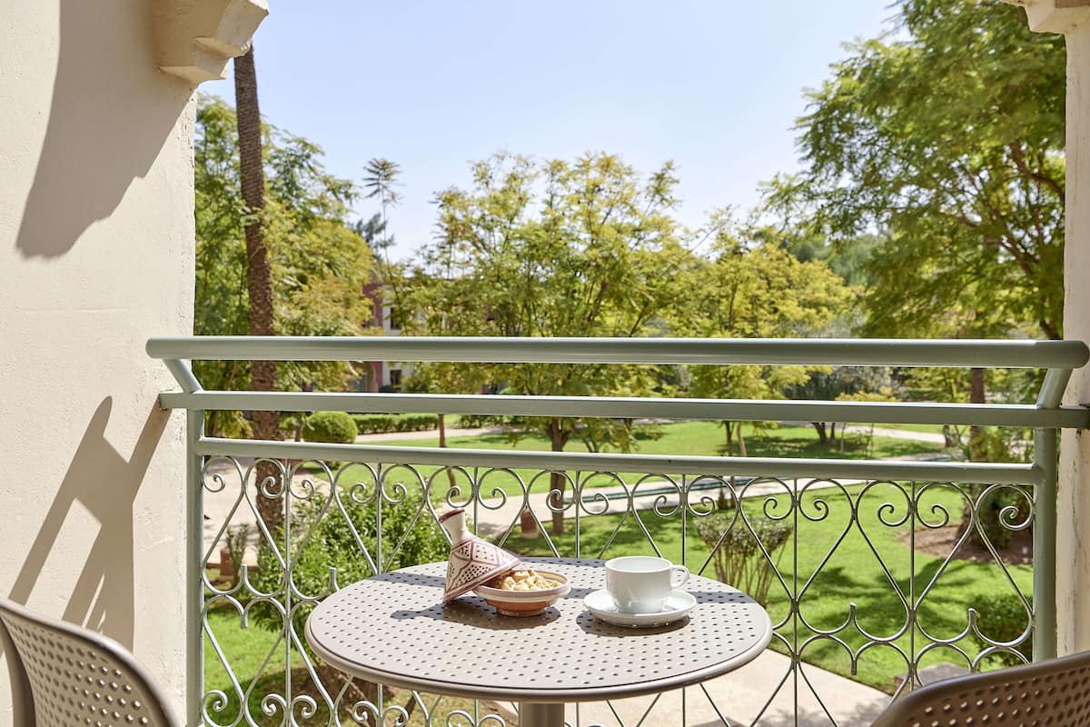 A balcony with a round table, a white cup, and a bowl of food.
