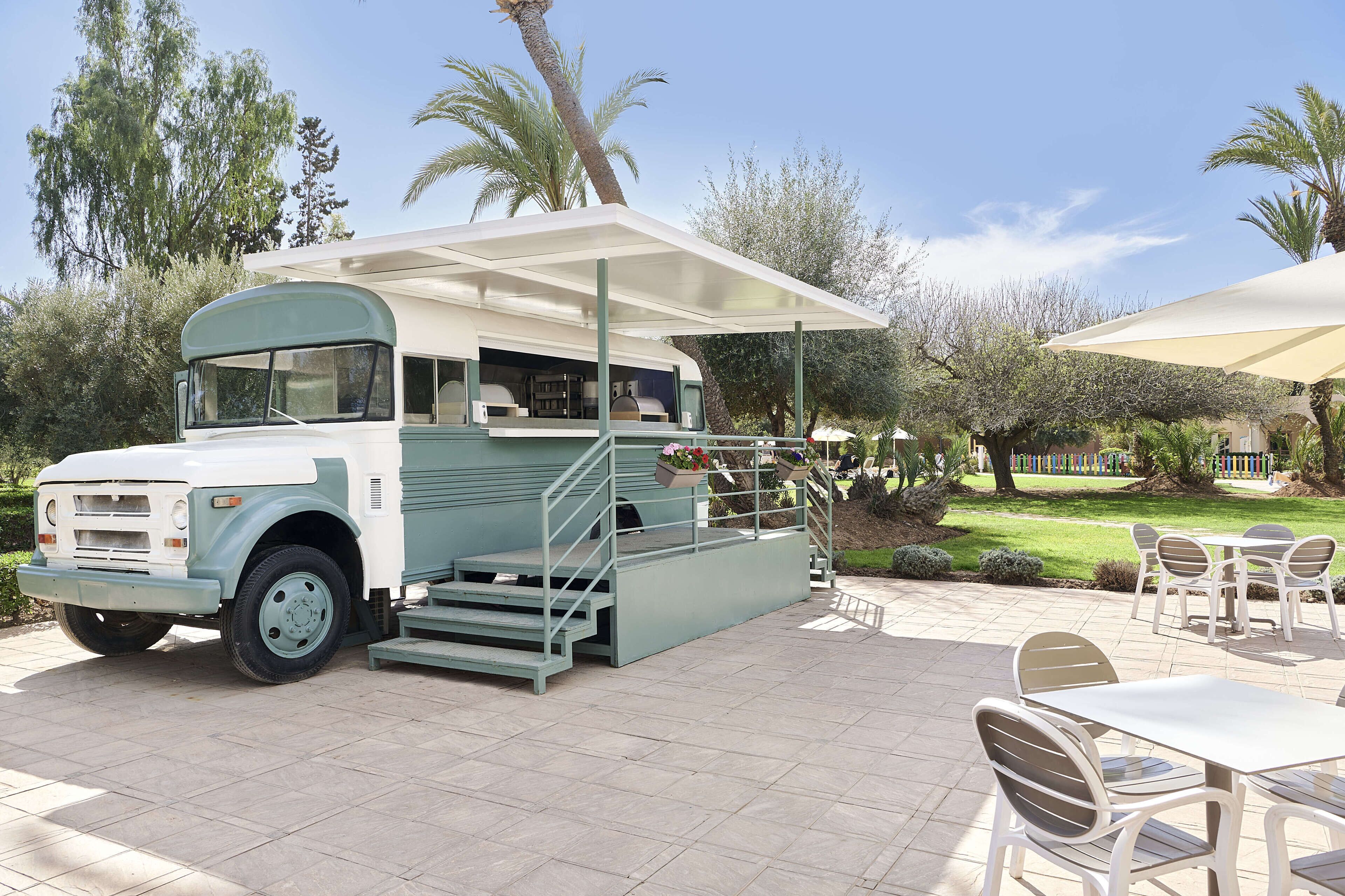Ein restaurierter Reisebus, umgebaut zu einem mobilen Café mit Außenbereich und überdachtem Platz.