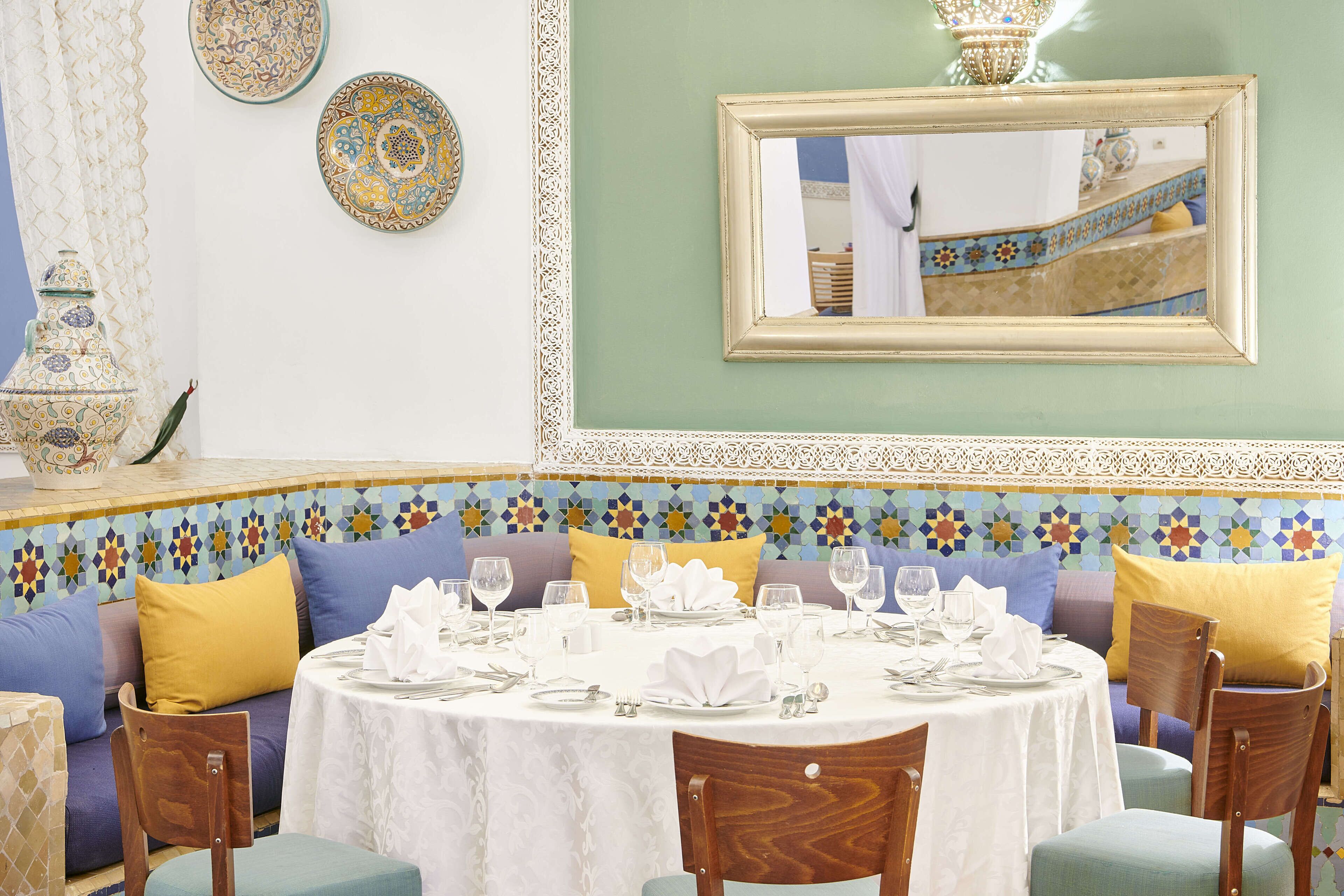 A dining area with a round table set for four, surrounded by wooden chairs.