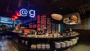A modern restaurant with a central counter, a neon sign, and a variety of dishes displayed. - Galleria 10 Hotel Bangkok (Bangkok)
