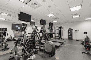 A gym with various exercise machines, a large mirror, and multiple screens. - Holiday Inn Express & Suites Gonzales by IHG (Gonzales)