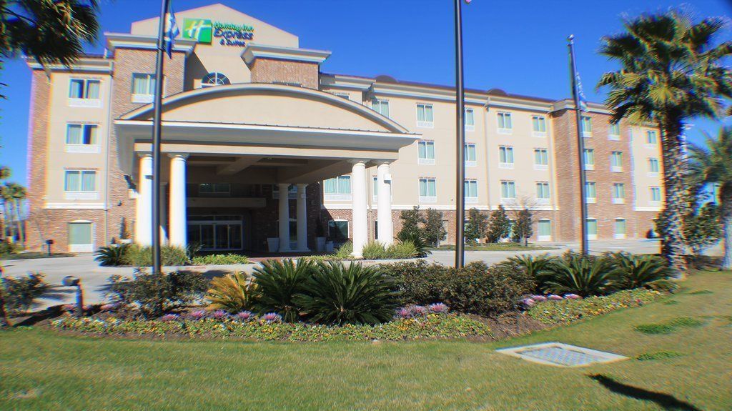 A hotel with a covered entrance, multiple floors, and a landscaped garden with palm trees.