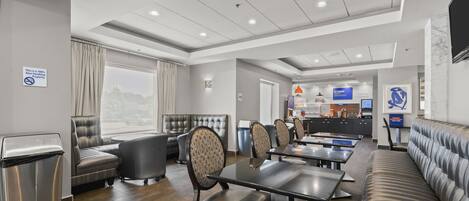 A modern hotel lobby with seating areas, a reception desk, and a view of the outside.
