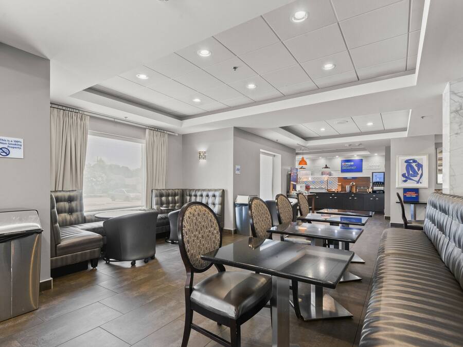 A modern hotel lobby with seating areas, a reception desk, and a view of the outside.