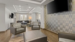 Ein modernes Wohnzimmer mit einem an der Wand montierten Flachbildfernseher, bequemen Sitzgelegenheiten und einer Wand mit Muster.