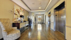 A hotel lobby with a reception desk, a patterned armchair, and an elevator. - Holiday Inn Express & Suites Gonzales by IHG (Gonzales)