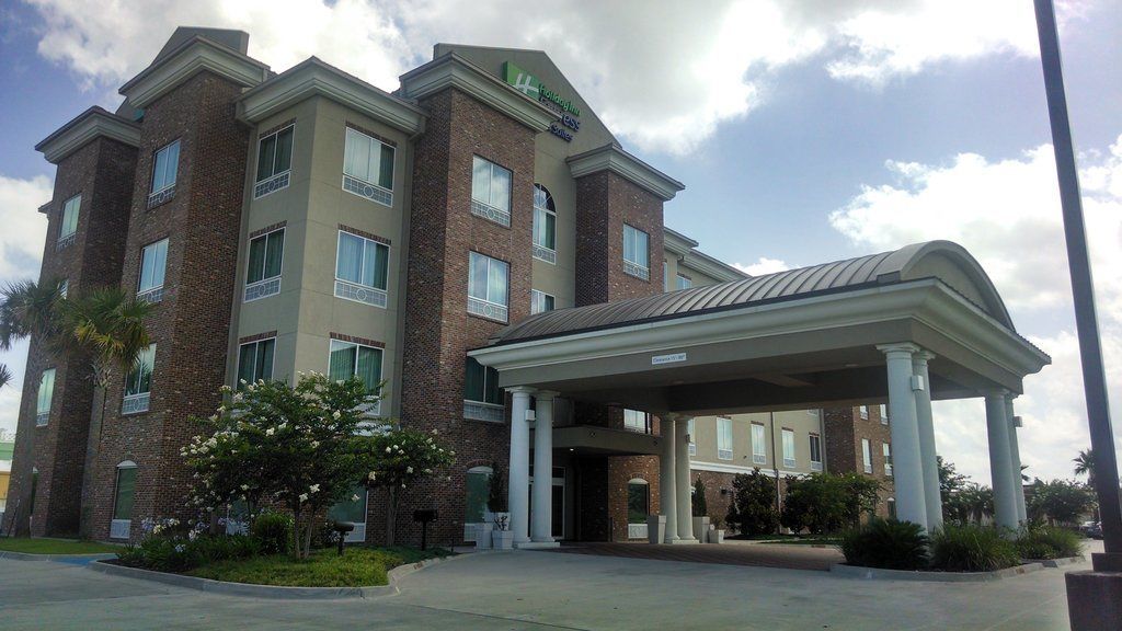 A multi-story hotel with a brick facade, a covered entrance, and a landscaped area with trees and shrubs.