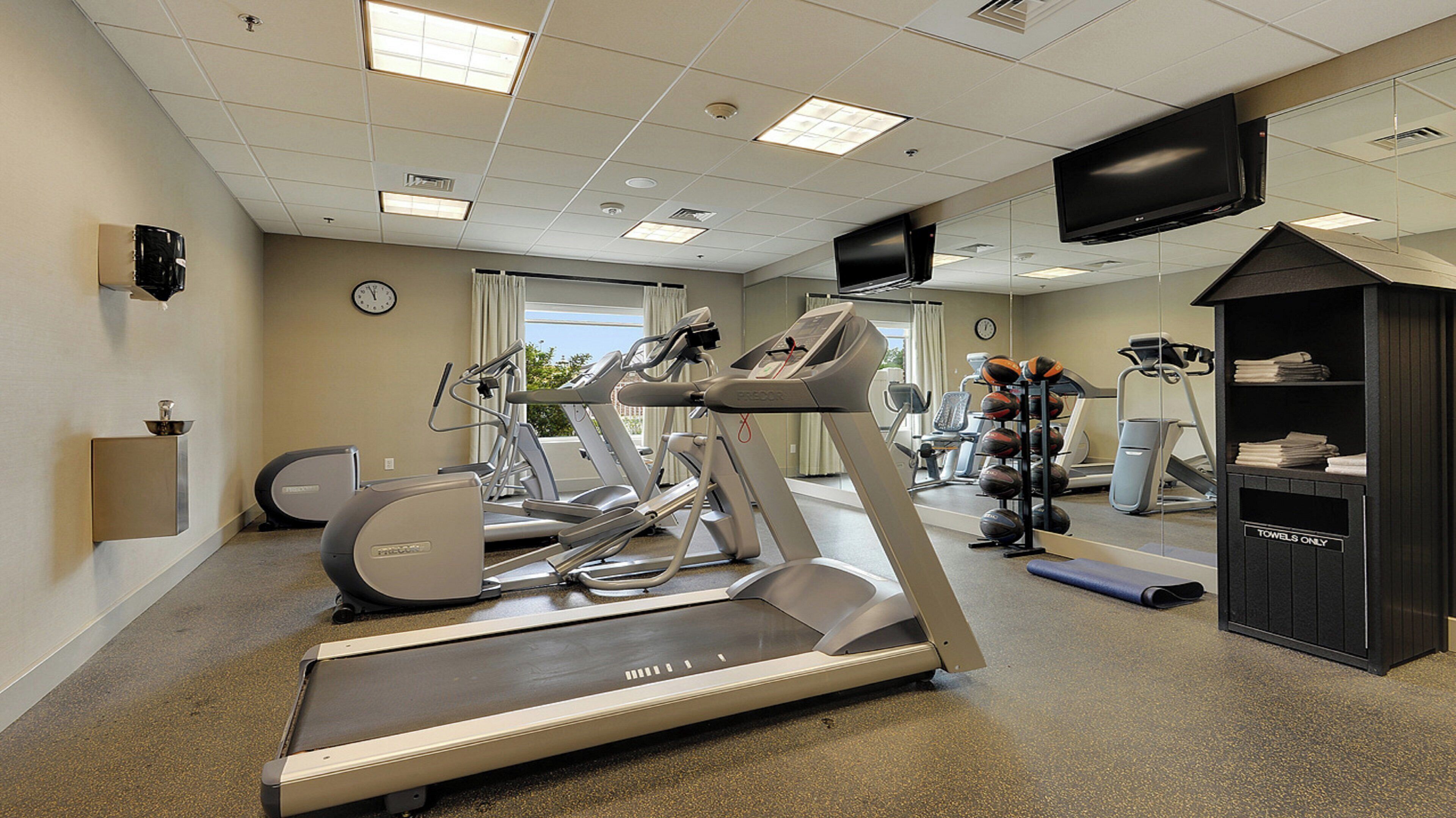 A fitness center with treadmills, stationary bikes, and a mirrored wall.