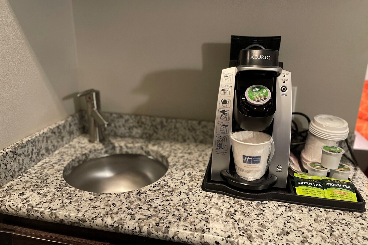 A Keurig coffee machine with a drip tray, a sink, and a countertop.