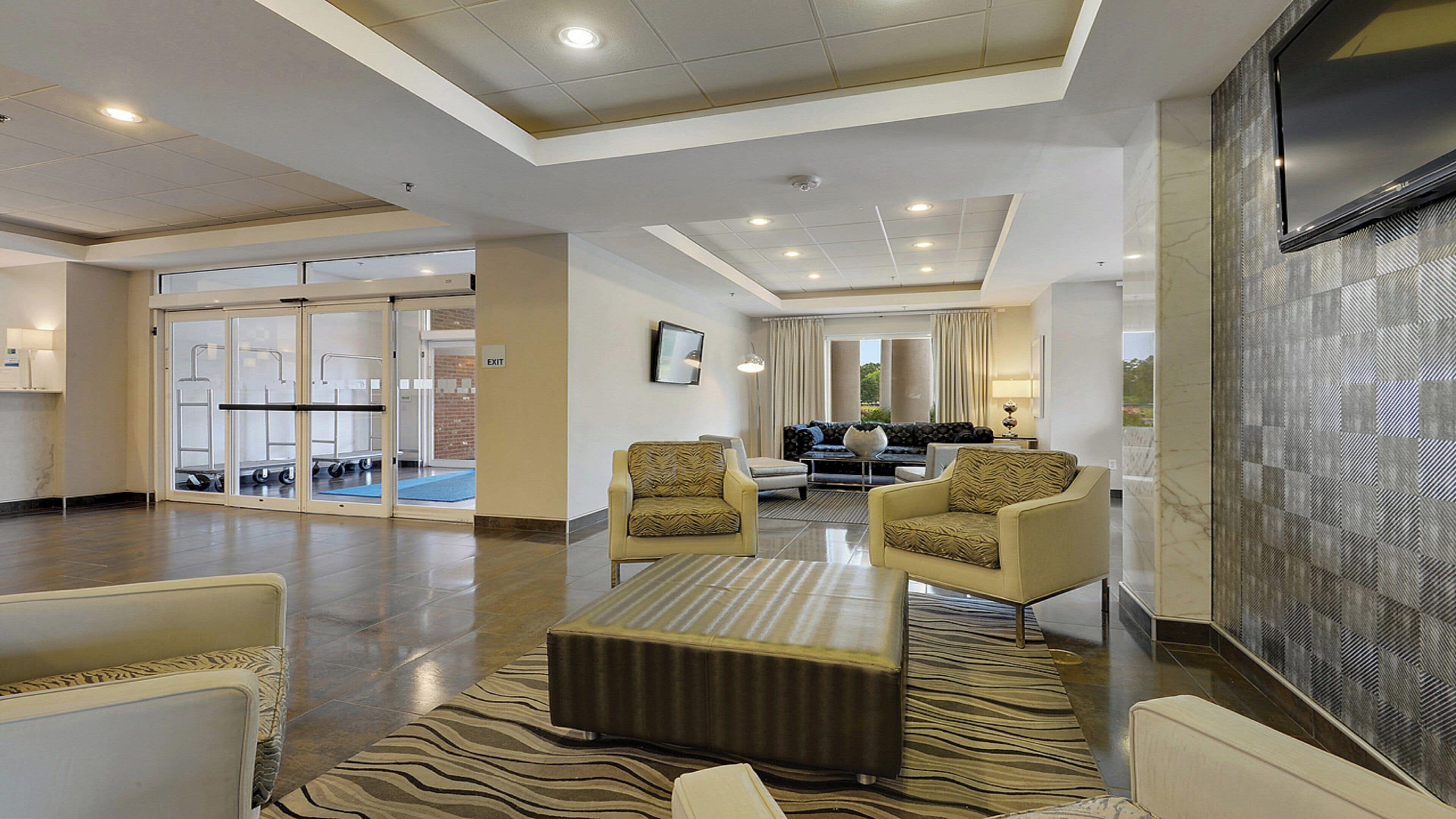 A spacious lobby with a seating area, a flat-screen TV, and a clear exit sign.