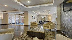 A spacious lobby with a seating area, a flat-screen TV, and a clear exit sign. - Holiday Inn Express & Suites Gonzales by IHG (Gonzales)