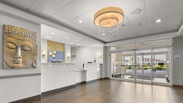 A reception area with a marble counter, a Buddha statue, and a glass door leading outside.