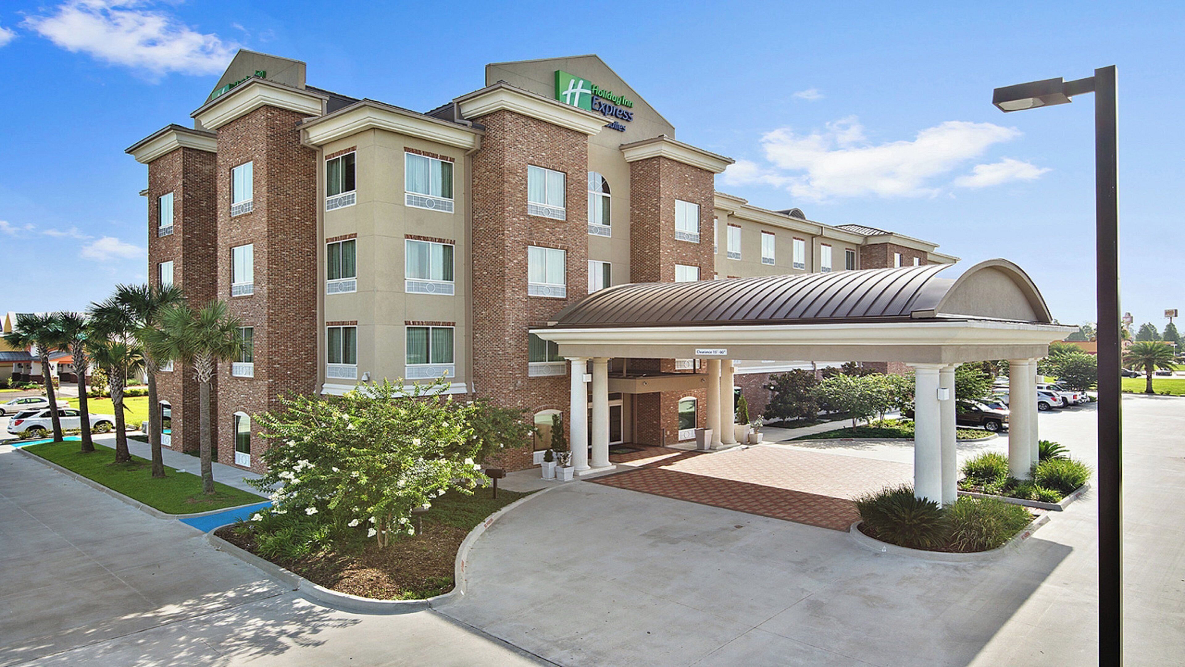 A Holiday Inn Express hotel with a covered entrance, brick facade, and a landscaped front yard.