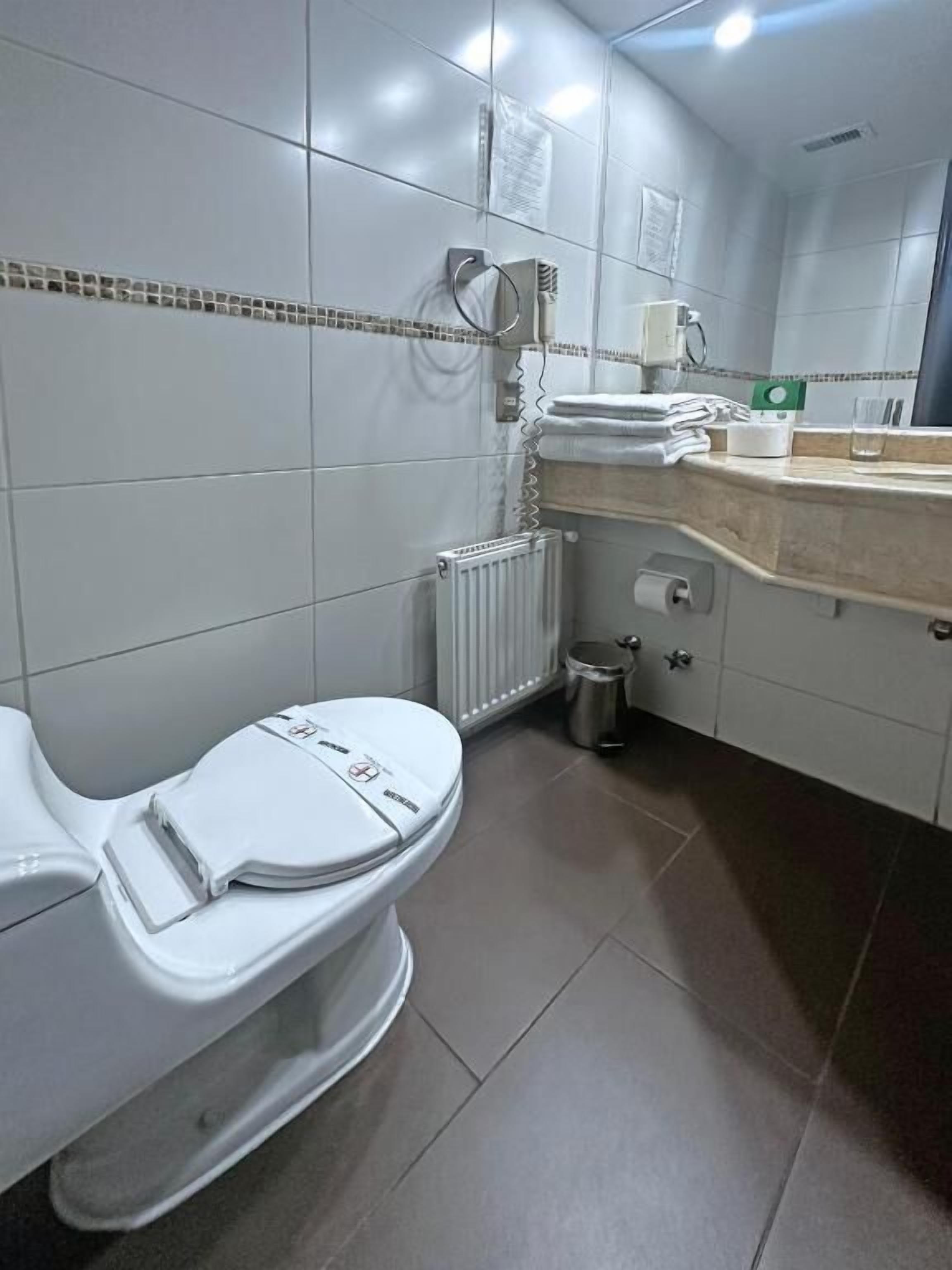 Un baño moderno con inodoro, lavamanos y espejo.