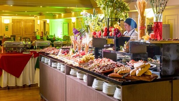 Un área de bufé con diferentes alimentos y un chef preparándolos.