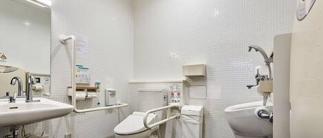 A modern bathroom with white fixtures, a toilet with a grab bar, a sink, and a bidet.