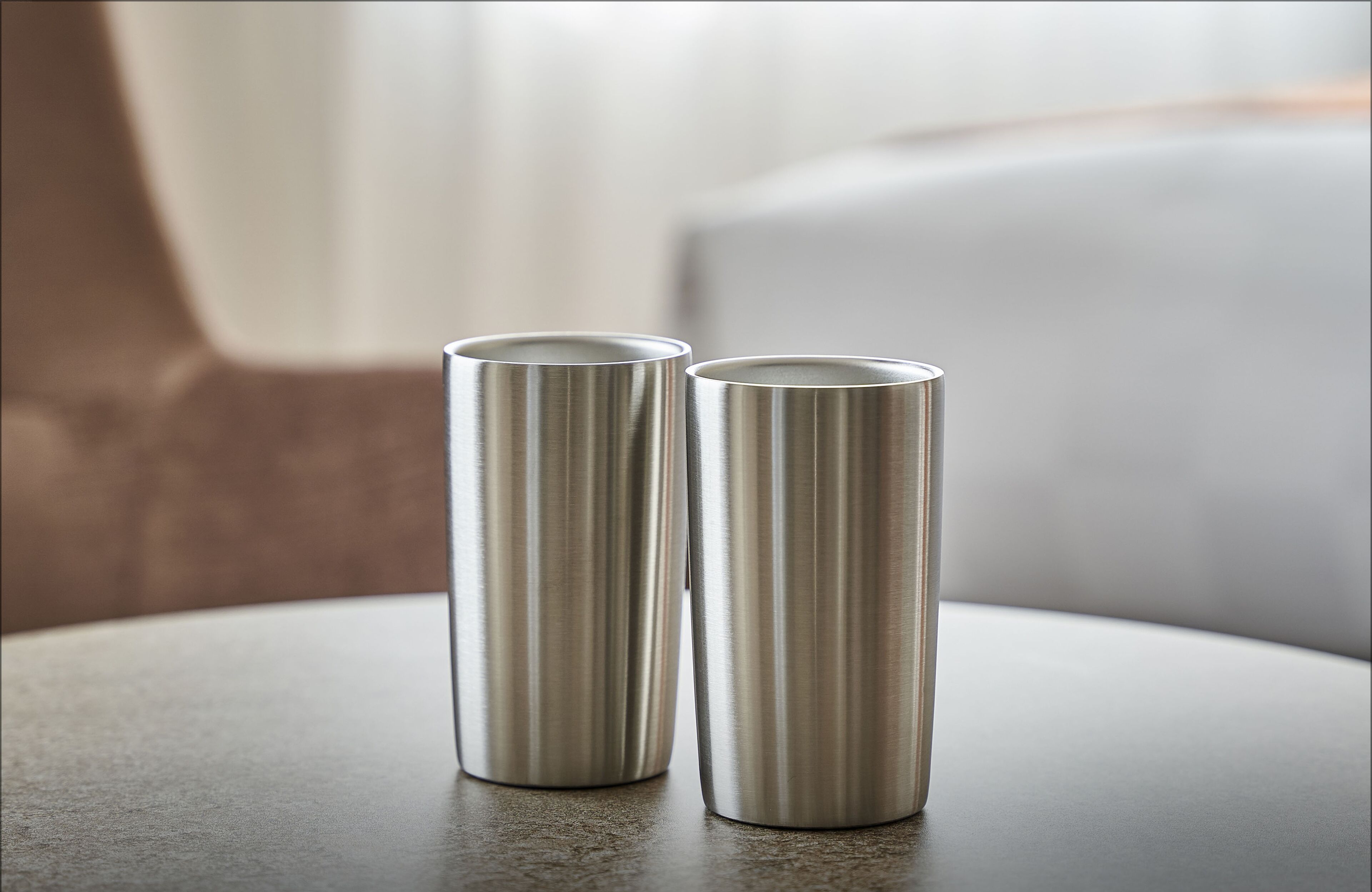 Two stainless steel candle holders on a table.