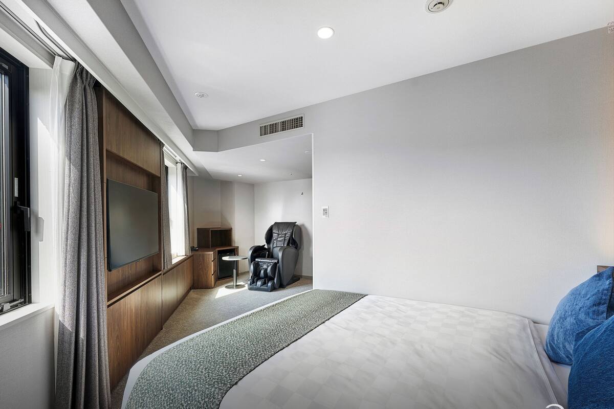 Ein Hotelzimmer mit Bett, Massagesessel, kleinem Tisch und Fernseher.