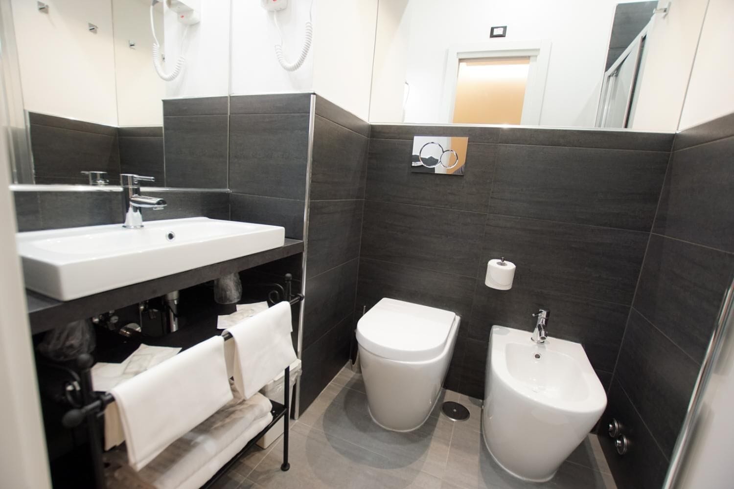 A modern bathroom with a large sink, bidet, and separate toilet.